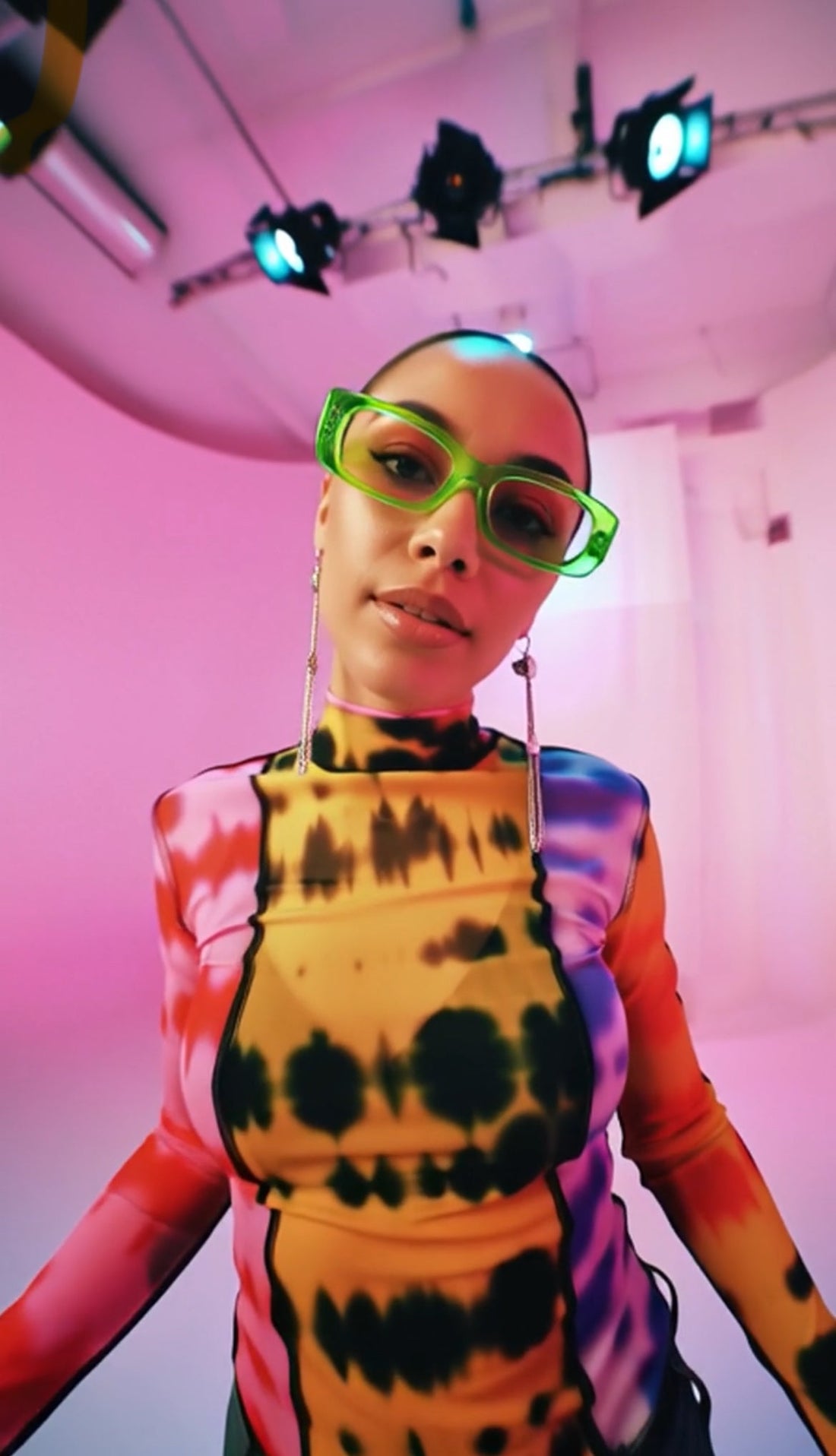 Person wearing a colorful outfit with neon sunglasses in a futuristic setting