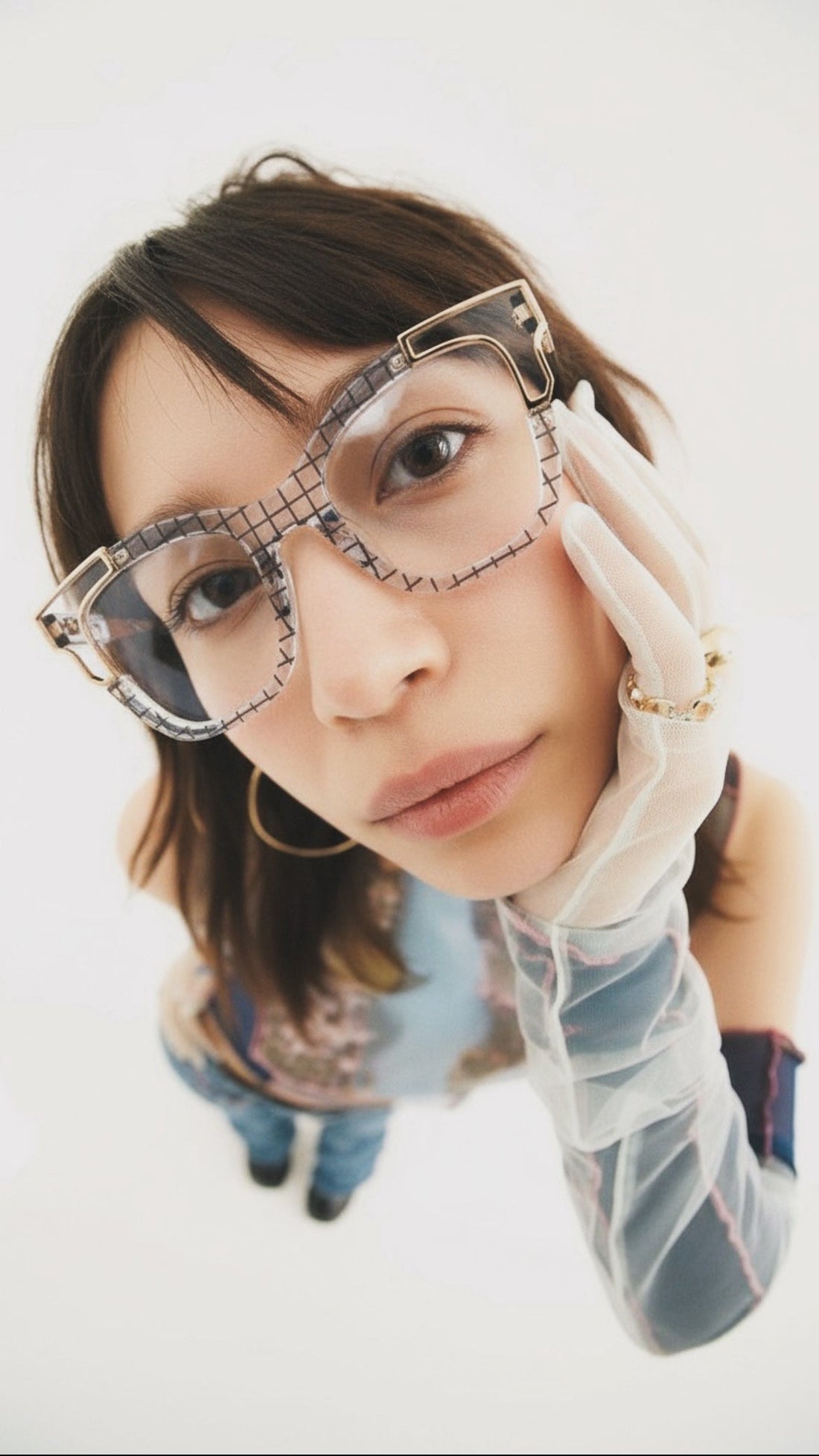 Person wearing diamond-studded glasses and a white glove on a white background