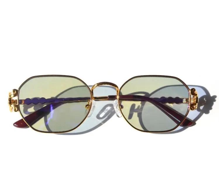 A pair of gold-colored sunglasses with crystals on the arms and a vintage finish.